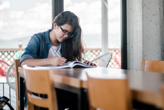 A female student is studying at her dining room table