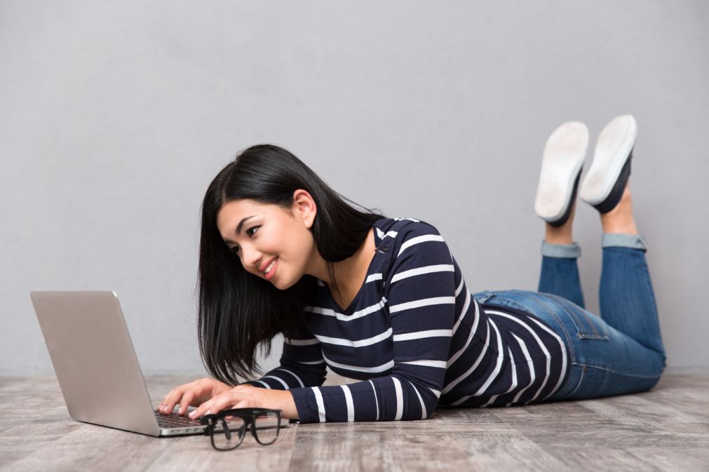 Online student with laptop laying on floor.