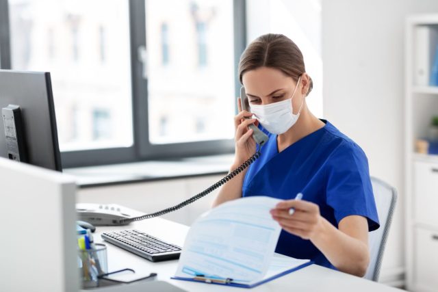 A female medical office administrator is on the phone in an office
